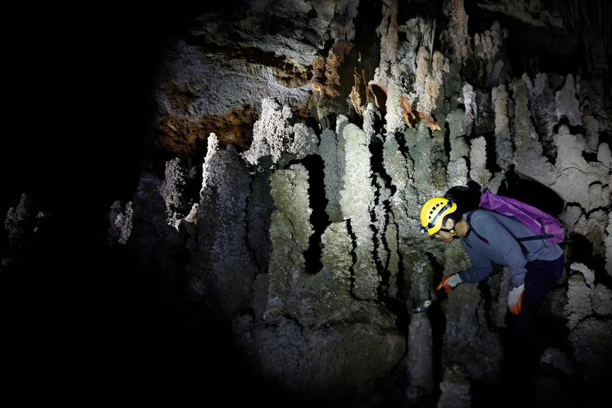 space-bermuda-triangle-cave Photograph of a scientist studying a stalagmite in a cave.